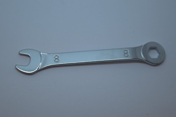 Combination wrench with open and box ends, size 8 mm, laid on a light surface for tightening hex nuts or bolts.